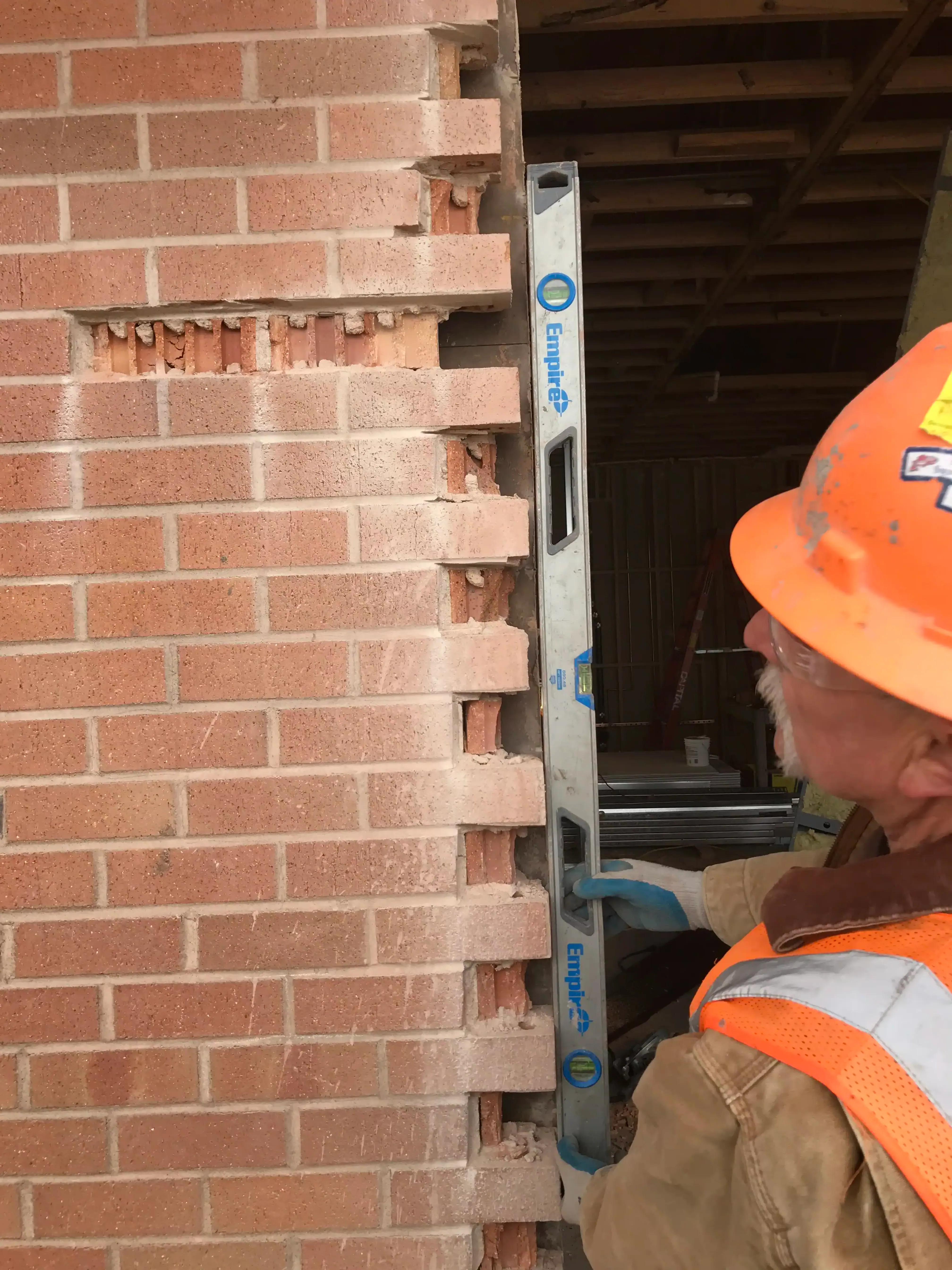 Photo showing a bubble level held up to the edge of brick veneer in which the original masonry is not plumb. Photo showing a bubble level held up to the edge of brick veneer in which the original masonry is not plumb.