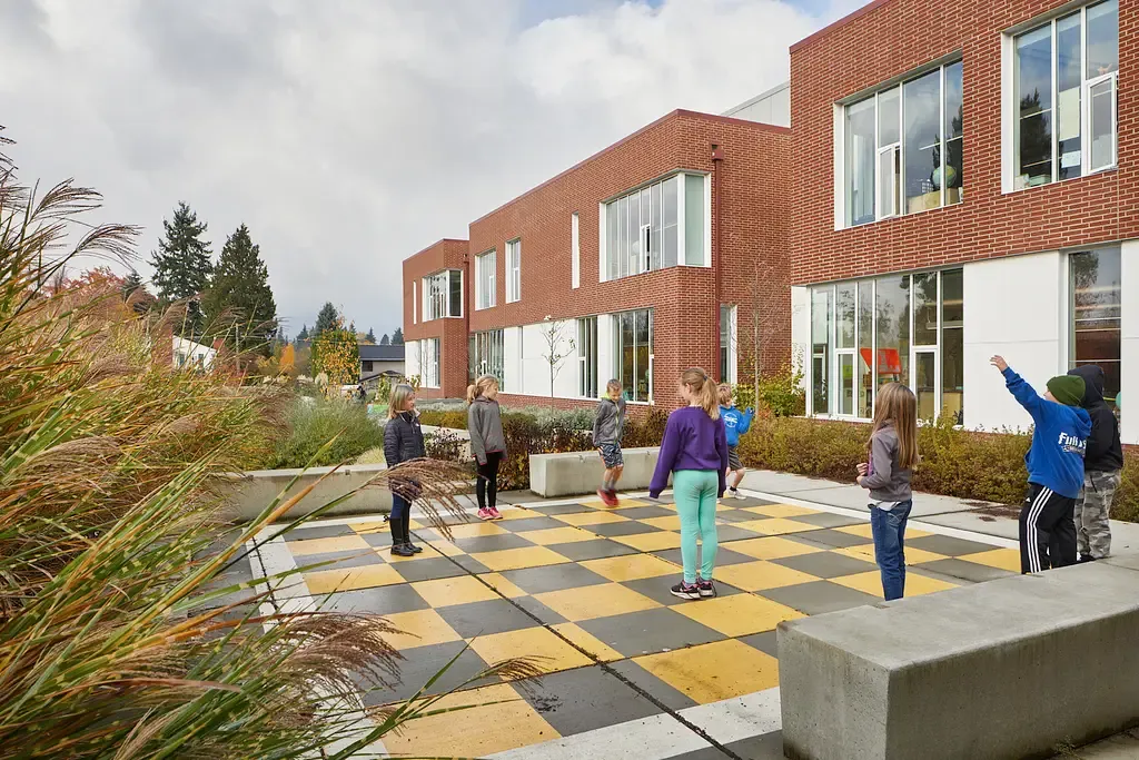 Photo taken outside the commons area featuring an outdoor checkers-board style concrete patio with children playing on it. Photo taken outside the commons area featuring an outdoor checkers-board style concrete patio with children playing on it.
