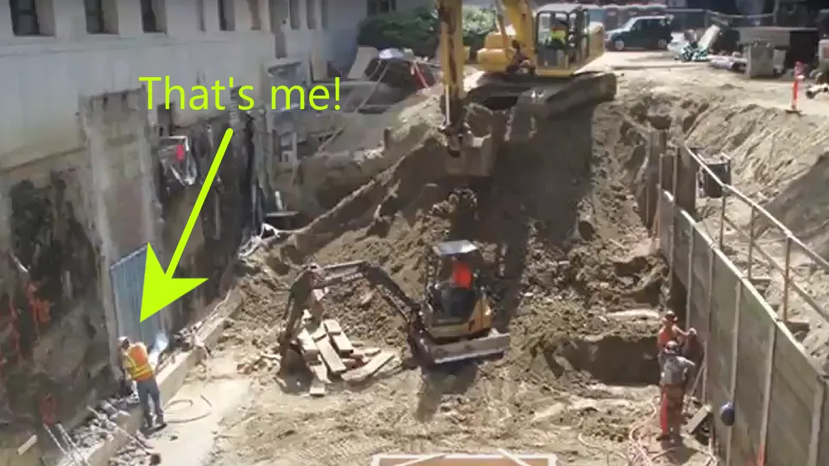 Mass excavationi behind the John L O'Brien building with workers at the bottom of the excavation. Text reads: 'Thats Me!' with an arrow indicating where Ryan is in the photo drilling into the building foundation.